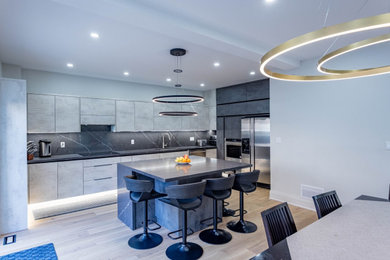 Example of a large single-wall vinyl floor kitchen pantry design in Toronto with flat-panel cabinets, gray cabinets, quartz countertops, black backsplash, quartz backsplash, an island and black countertops
