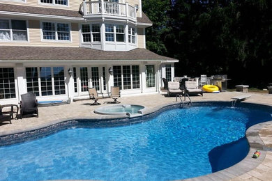Example of a large backyard custom-shaped pool design in Portland Maine