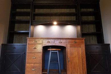 Modelo de despacho rústico de tamaño medio sin chimenea con biblioteca, paredes grises, suelo de madera en tonos medios, escritorio independiente y suelo marrón