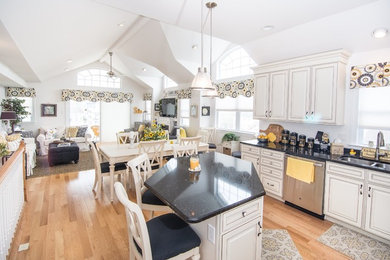 Example of a mid-sized eclectic u-shaped light wood floor open concept kitchen design in Philadelphia with a double-bowl sink, white cabinets, stainless steel appliances, an island, raised-panel cabinets and granite countertops