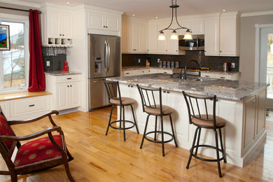 Eat-in kitchen - mid-sized transitional l-shaped light wood floor eat-in kitchen idea in Other with an undermount sink, raised-panel cabinets, white cabinets, granite countertops, gray backsplash, glass tile backsplash, stainless steel appliances and an island