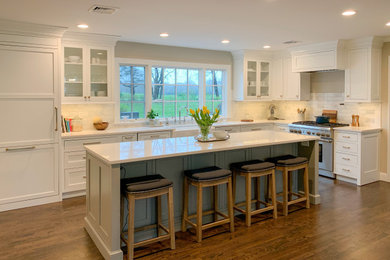 Mid-sized transitional l-shaped dark wood floor and brown floor eat-in kitchen photo in Other with a farmhouse sink, shaker cabinets, white cabinets, white backsplash, subway tile backsplash, stainless steel appliances, an island and white countertops