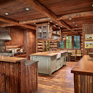 Imagen de cocina rural, extra grande, con fregadero sobremueble, armarios con paneles lisos, puertas de armario de madera en tonos medios, encimera de madera, salpicadero marrón, electrodomésticos con paneles, suelo de madera oscura, dos o más islas, salpicadero de madera y suelo marrón