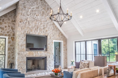 Large eclectic open concept medium tone wood floor living room photo in Other with white walls, a standard fireplace, a stone fireplace and a wall-mounted tv