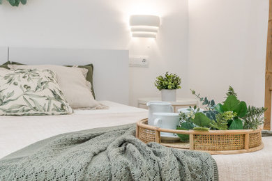 Foto de dormitorio principal y blanco nórdico de tamaño medio sin chimenea con paredes blancas, suelo de madera en tonos medios y suelo marrón