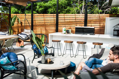This is an example of a mid-sized transitional backyard deck in Sydney with an outdoor kitchen and a pergola.