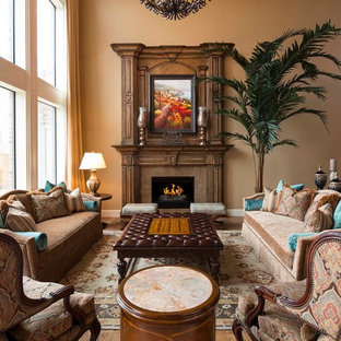 Foto de salón para visitas abierto, mediterráneo, grande, con paredes beige, suelo de madera en tonos medios, chimenea tradicional y marco de chimenea de madera