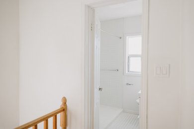 Example of a minimalist ceramic tile and white floor hallway design in Toronto with white walls