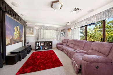 This is an example of a small eclectic enclosed home theatre in Sydney with grey walls, carpet and a projector screen.