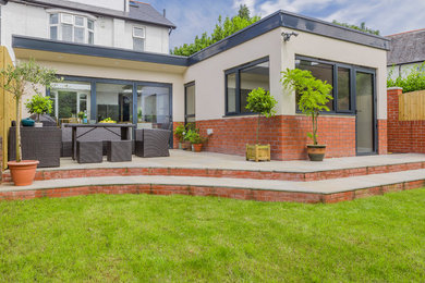 Mid-sized contemporary beige one-story brick exterior home idea in Cardiff with a tile roof