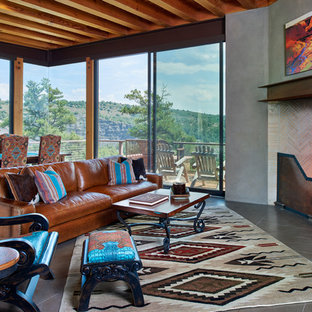 Offenes Mediterranes Wohnzimmer mit grauer Wandfarbe, Kamin, gefliestem Kaminsims und grauem Boden in Albuquerque