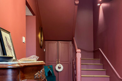 Cette image montre un petit vestibule traditionnel avec un mur violet, un sol en carrelage de céramique, une porte simple, une porte en bois clair, un sol noir et boiseries.