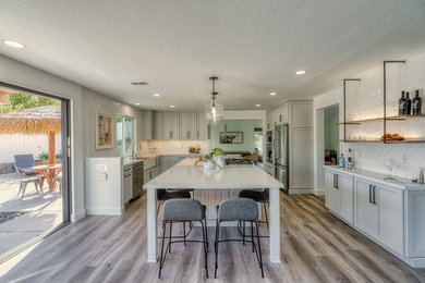 Inspiration for a mid-sized coastal u-shaped eat-in kitchen remodel in San Diego with shaker cabinets, white cabinets, quartz countertops and an island