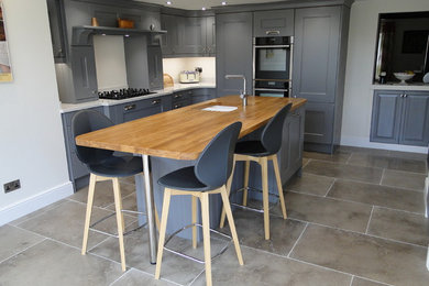 Design ideas for a medium sized contemporary l-shaped enclosed kitchen in Other with a submerged sink, shaker cabinets, grey cabinets, quartz worktops, stainless steel appliances, limestone flooring, an island, grey floors and white worktops.