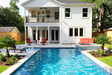 Photo of a large traditional backyard custom-shaped pool in Houston with a hot tub and concrete pavers.