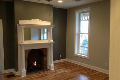 Inspiration for a timeless medium tone wood floor living room remodel in Boston with a standard fireplace and a wood fireplace surround