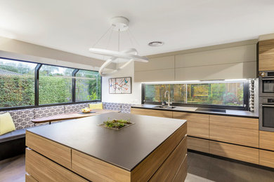 Inspiration for a mid-sized modern l-shaped open plan kitchen in Melbourne with a double-bowl sink, flat-panel cabinets, light wood cabinets, solid surface benchtops, stainless steel appliances, with island, grey floor and black benchtop.