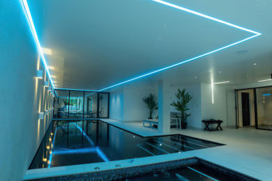 Large modern indoor swimming pool in Other with a pool house.