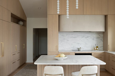 Example of a minimalist u-shaped light wood floor and vaulted ceiling kitchen design in Denver with flat-panel cabinets, light wood cabinets, marble countertops, stone slab backsplash, paneled appliances and an island