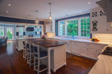 This is an example of a traditional u-shaped separate kitchen in DC Metro with shaker cabinets, white cabinets, white splashback, glass tile splashback, dark hardwood floors and with island.