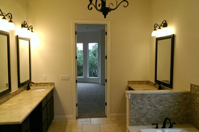 Drop-in bathtub - traditional travertine floor drop-in bathtub idea in Austin with raised-panel cabinets and dark wood cabinets