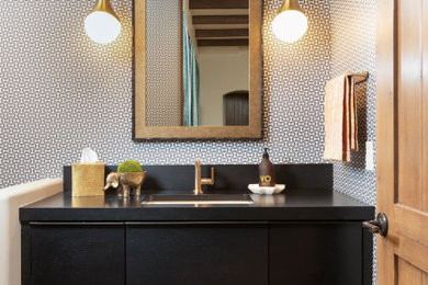 This is an example of a mid-sized midcentury powder room in Phoenix with flat-panel cabinets, black cabinets, grey walls, ceramic floors, an undermount sink, wood benchtops, black floor, black benchtops, a floating vanity and wallpaper.