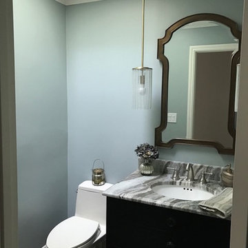 Light green walls with brown and marble sink with a vanity mirror