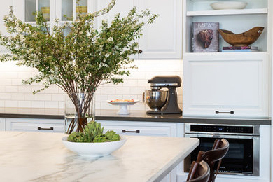 Inspiration for a mid-sized timeless l-shaped dark wood floor kitchen remodel in San Diego with a farmhouse sink, raised-panel cabinets, white cabinets, quartz countertops, white backsplash, subway tile backsplash, stainless steel appliances and an island