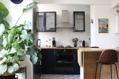 Inspiration pour une petite cuisine américaine minimaliste en L avec des portes de placard bleues, un plan de travail en bois, une crédence blanche, aucun îlot et un plan de travail marron.