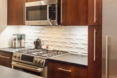 Example of a mid-sized classic galley medium tone wood floor and brown floor enclosed kitchen design in New York with flat-panel cabinets, soapstone countertops, ceramic backsplash, stainless steel appliances, an island, an undermount sink, dark wood cabinets and white backsplash