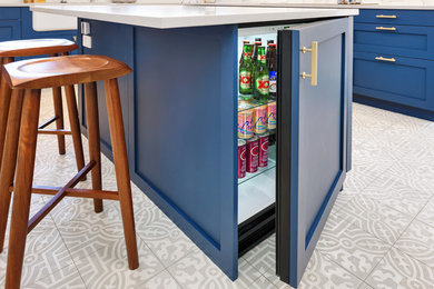 Example of a large transitional l-shaped porcelain tile and white floor enclosed kitchen design in Chicago with a farmhouse sink, shaker cabinets, blue cabinets, quartzite countertops, white backsplash, marble backsplash, paneled appliances and an island