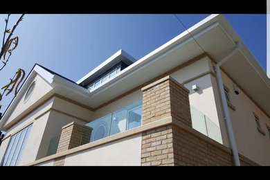 This is an example of an expansive and beige contemporary detached house in Dorset with three floors, mixed cladding, a hip roof and a tiled roof.