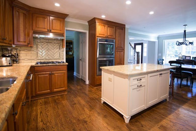 Inspiration for a mid-sized timeless l-shaped medium tone wood floor eat-in kitchen remodel in Atlanta with an undermount sink, raised-panel cabinets, medium tone wood cabinets, granite countertops, beige backsplash, ceramic backsplash, stainless steel appliances and an island