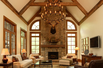 This is an example of a country enclosed family room in Atlanta with beige walls, travertine floors, a standard fireplace, a stone fireplace surround, a wall-mounted tv and beige floor.