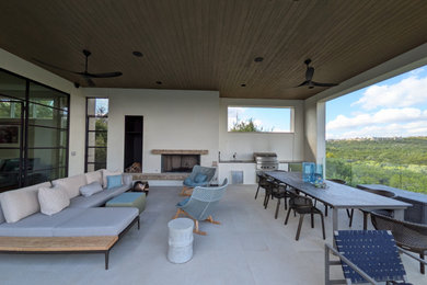 Example of a large trendy backyard stone patio kitchen design in Austin with a roof extension
