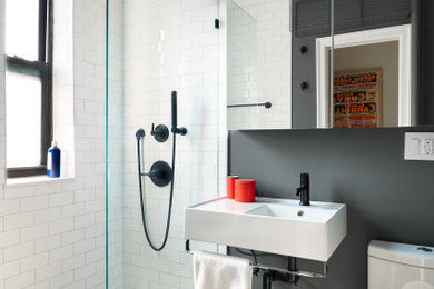 Example of a trendy 3/4 white tile and subway tile gray floor and single-sink alcove shower design in New York with white cabinets, a two-piece toilet, black walls, a wall-mount sink, white countertops and a floating vanity