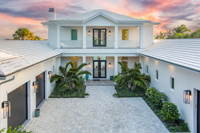 Inspiration for a large transitional white two-story concrete house exterior remodel in Miami with a hip roof, a tile roof and a white roof