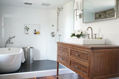 Mid-sized country white tile and subway tile medium tone wood floor and brown floor bathroom photo in Philadelphia with furniture-like cabinets, medium tone wood cabinets, white walls, a drop-in sink and wood countertops