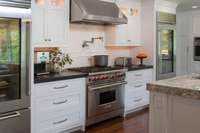 Elegant eat-in kitchen photo in Philadelphia with a farmhouse sink, flat-panel cabinets, white cabinets, granite countertops, white backsplash and stainless steel appliances