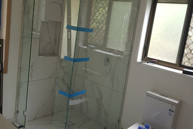 Kleines Modernes Badezimmer En Suite mit weißen Schränken, Eckdusche, Wandtoilette mit Spülkasten, weißen Fliesen, Keramikfliesen, weißer Wandfarbe, Keramikboden, Quarzwerkstein-Waschtisch, weißem Boden und Falttür-Duschabtrennung in Brisbane