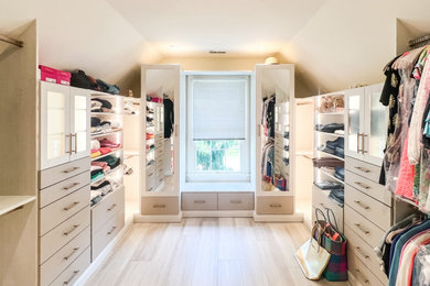 Mid-sized transitional women's vinyl floor, beige floor and vaulted ceiling walk-in closet photo with flat-panel cabinets and light wood cabinets