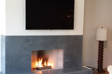 Living room - eclectic medium tone wood floor living room idea in New York with a standard fireplace, a concrete fireplace and a wall-mounted tv