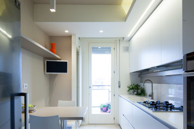 Small modern galley eat-in kitchen in Venice with a drop-in sink, flat-panel cabinets, white cabinets, white splashback, stainless steel appliances and white floor.