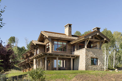 Large mountain style brown two-story stone and clapboard house exterior photo in Salt Lake City with a shed roof, a metal roof and a brown roof
