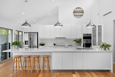 Inspiration for a contemporary galley kitchen in Adelaide with an undermount sink, flat-panel cabinets, white cabinets, grey splashback, stainless steel appliances, medium hardwood floors, with island, brown floor, grey benchtop and vaulted.