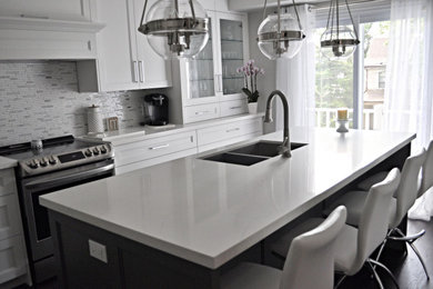 Inspiration for a mid-sized transitional l-shaped separate kitchen in Toronto with an undermount sink, shaker cabinets, white cabinets, quartz benchtops, multi-coloured splashback, porcelain splashback, stainless steel appliances, medium hardwood floors, with island, brown floor and white benchtop.