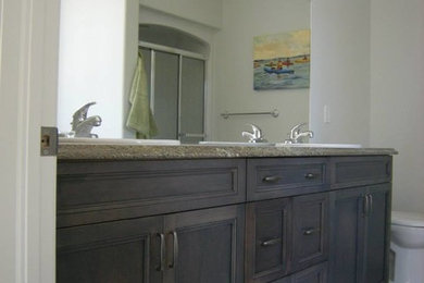 Transitional master porcelain tile alcove shower photo in Toronto with beaded inset cabinets, dark wood cabinets, white walls, a drop-in sink and granite countertops