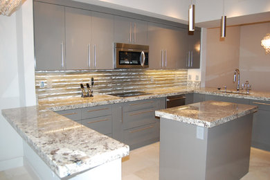 Photo of a large contemporary open plan kitchen in Miami with an undermount sink, flat-panel cabinets, grey cabinets, granite benchtops, metallic splashback, metal splashback, stainless steel appliances, multiple islands and beige floor.