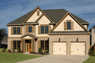 Large traditional beige two-story stone exterior home idea in Detroit with a clipped gable roof