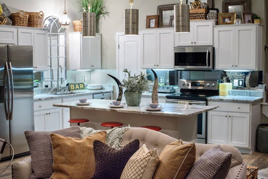 Inspiration for a mid-sized contemporary l-shaped light wood floor and beige floor eat-in kitchen remodel in New Orleans with a double-bowl sink, beaded inset cabinets, white cabinets, granite countertops, stainless steel appliances, an island, metallic backsplash and mirror backsplash